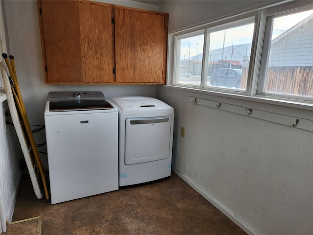 clothes washing area with cabinets and washing machine and dryer