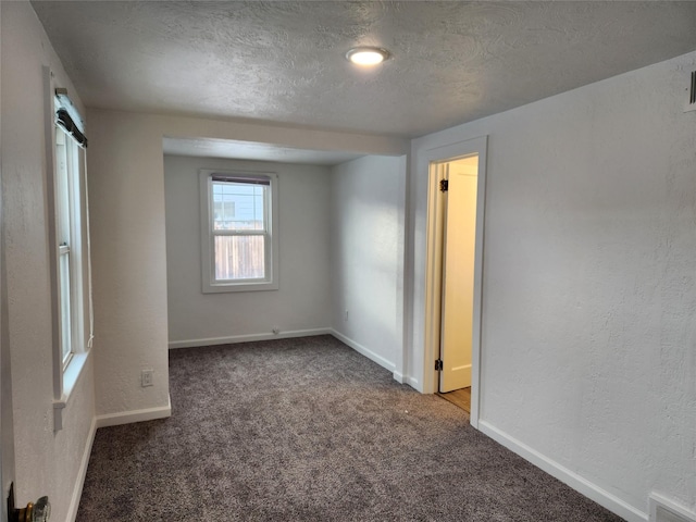 unfurnished room with dark colored carpet and a textured ceiling