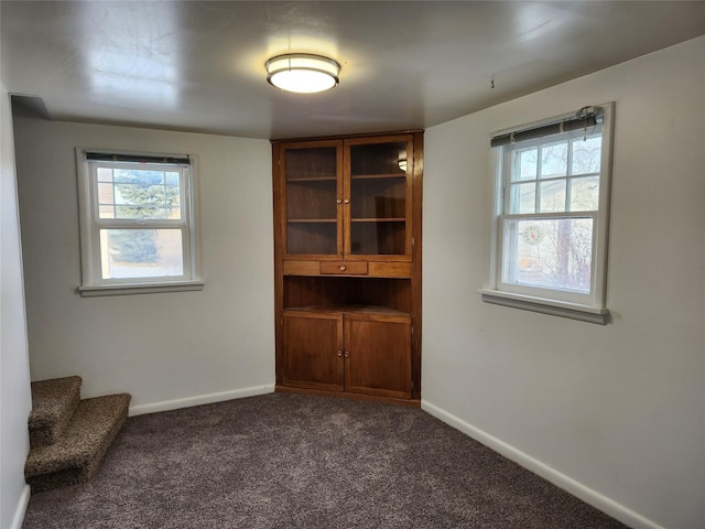 unfurnished room with dark carpet and a healthy amount of sunlight