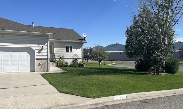 view of side of property with a mountain view, a garage, and a lawn