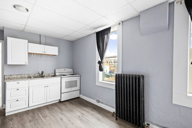 kitchen featuring radiator, a paneled ceiling, white electric range, white cabinets, and sink