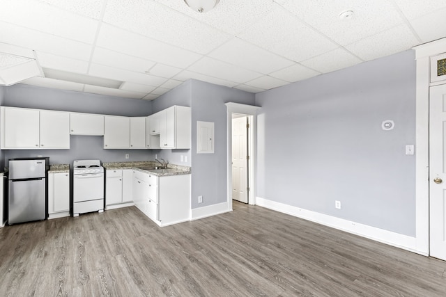 kitchen featuring white gas range, light wood-type flooring, stainless steel refrigerator, a paneled ceiling, and white cabinets