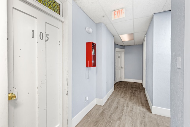 hall with a paneled ceiling and light hardwood / wood-style floors