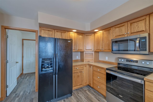 kitchen with light wood-type flooring, light brown cabinets, and stainless steel appliances