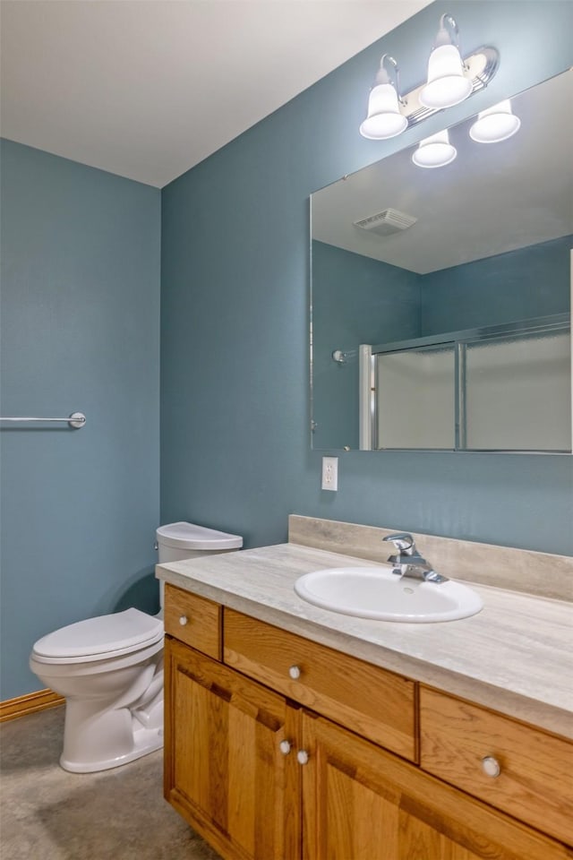 bathroom with vanity, a shower with door, and toilet