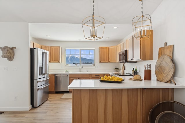 211 Mcwenneger Dr, Kalispell, MT 59901 - kitchen with appliances with stainless steel finishes, a peninsula, a chandelier, light wood-type flooring, and light countertops