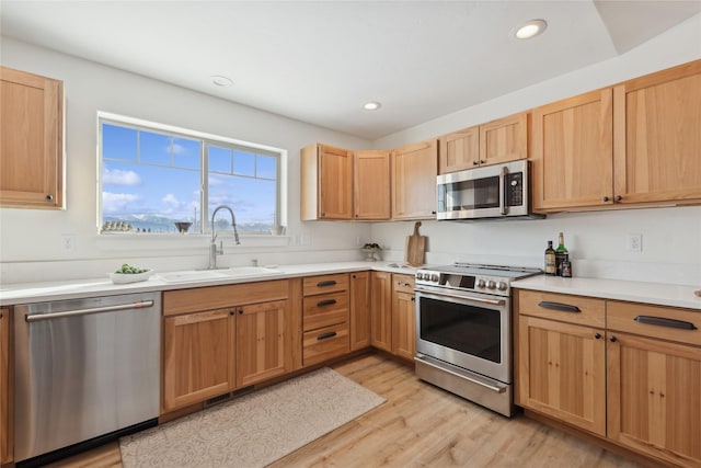 kitchen with appliances with stainless steel finishes, a peninsula, a sink, light countertops, and a notable chandelier