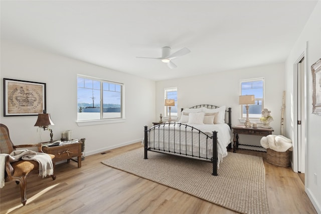 bedroom with baseboards, ceiling fan, visible vents, and light wood finished floors