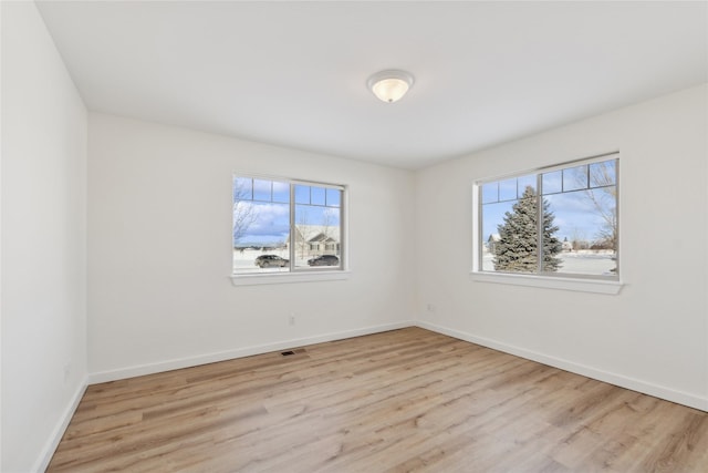 empty room featuring light wood-type flooring, baseboards, and visible vents