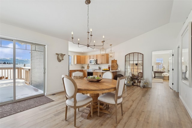 living area with light wood finished floors, baseboards, high vaulted ceiling, and an inviting chandelier