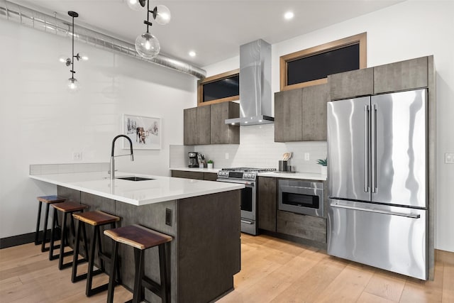 206 Lupfer Ave Unit 105, Whitefish, MT 59937 - kitchen with stainless steel appliances, wall chimney range hood, a sink, a kitchen breakfast bar, and light wood finished floors