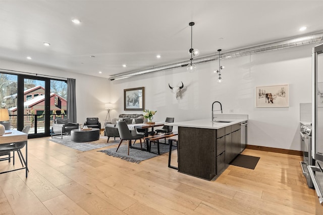 kitchen with kitchen peninsula, dark brown cabinetry, light hardwood / wood-style flooring, stainless steel dishwasher, and sink