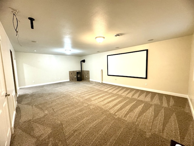 home theater room featuring baseboards, carpet flooring, and a wood stove