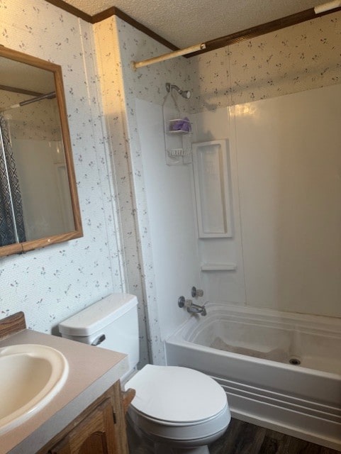 bathroom featuring a textured ceiling, wood finished floors, vanity, and wallpapered walls