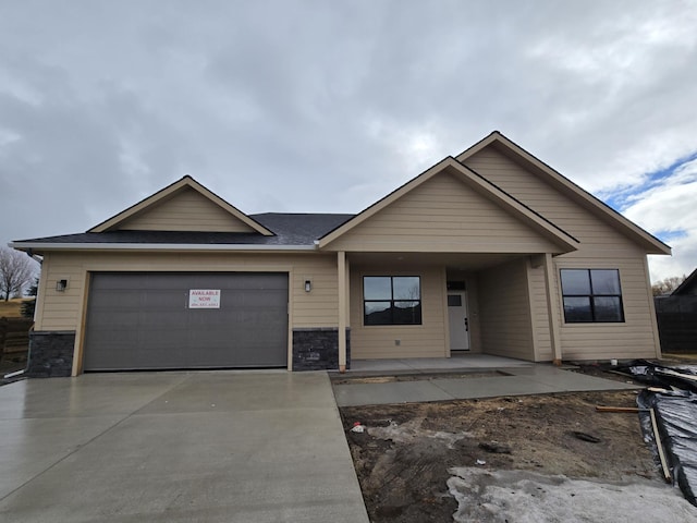 ranch-style house with stone siding, a garage, and driveway