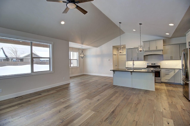 kitchen featuring pendant lighting, dark countertops, gray cabinetry, appliances with stainless steel finishes, and a sink