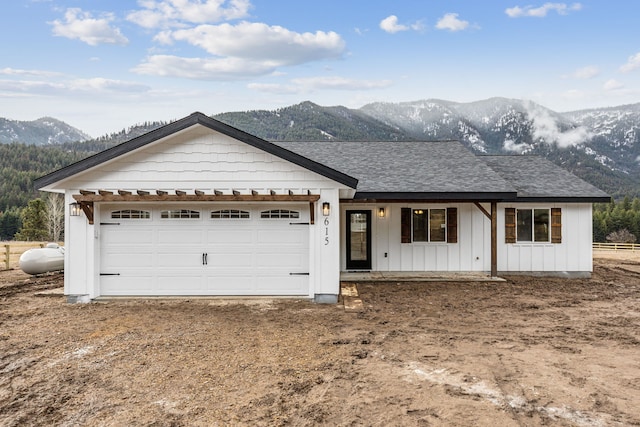 ranch-style home featuring a shingled roof, an attached garage, board and batten siding, a mountain view, and driveway