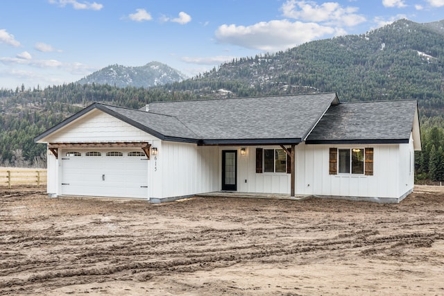 view of front facade with a garage, a mountain view, and a shingled roof