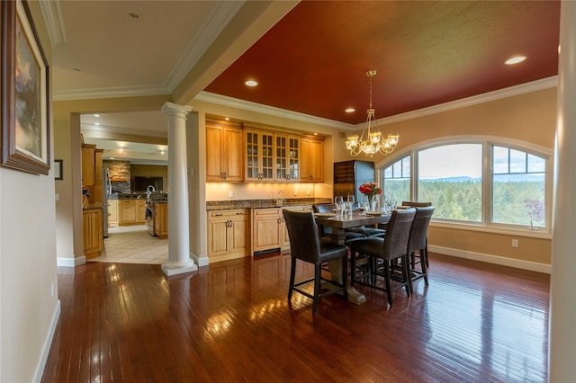 dining area featuring crown molding, wood finished floors, and ornate columns