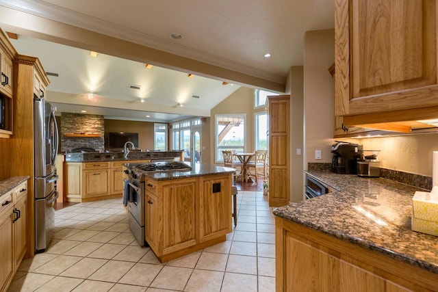 kitchen with lofted ceiling with beams, a kitchen island, dark stone countertops, stainless steel appliances, and light tile patterned flooring