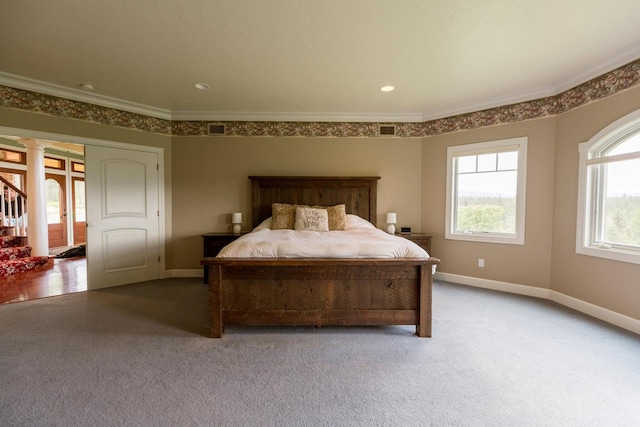 carpeted bedroom featuring ornamental molding, baseboards, visible vents, and ornate columns