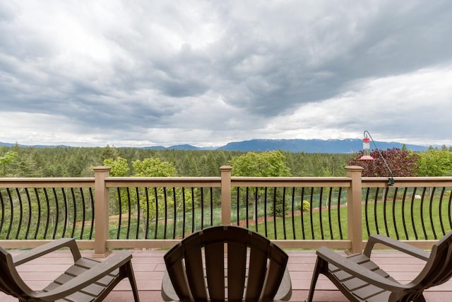 wooden terrace featuring a mountain view, a wooded view, and a yard