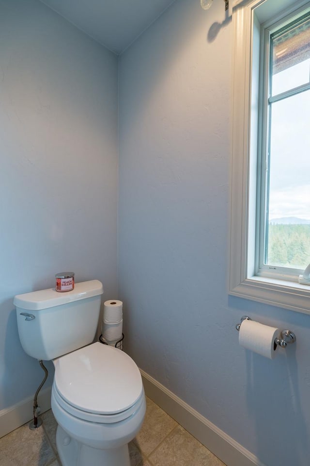 bathroom featuring tile patterned flooring, baseboards, and toilet