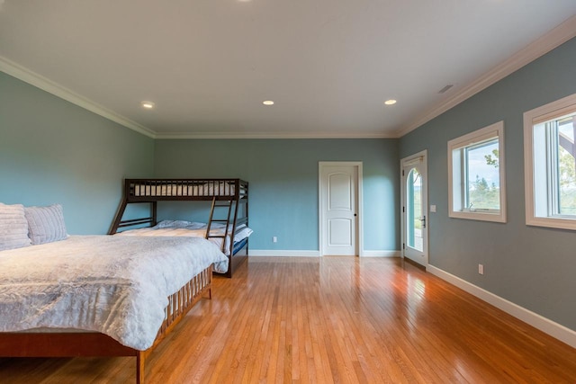 bedroom featuring ornamental molding, light wood-type flooring, visible vents, and baseboards