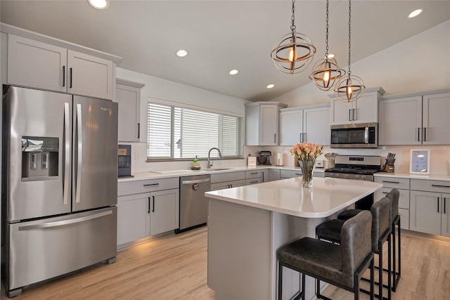 kitchen featuring stainless steel appliances, a breakfast bar, a sink, a kitchen island, and light countertops