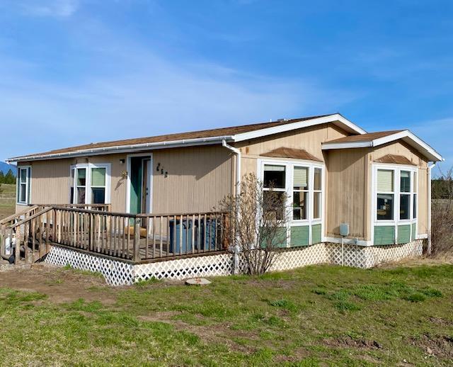 back of property featuring a deck and a lawn