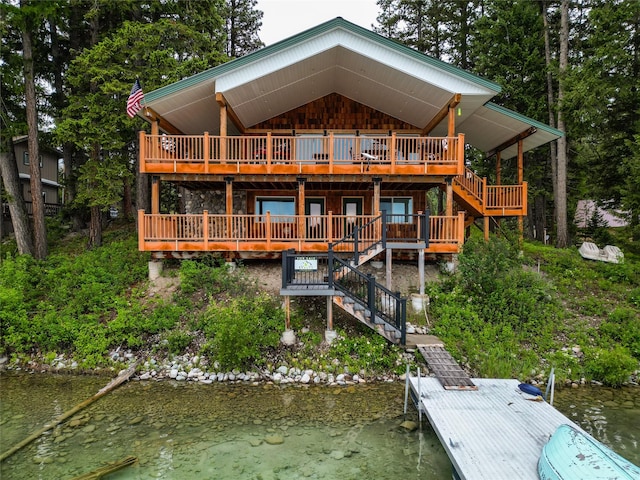 rear view of property featuring a deck with water view and stairs