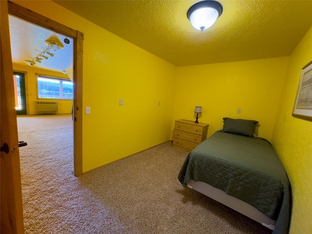 carpeted bedroom featuring a textured ceiling and heating unit