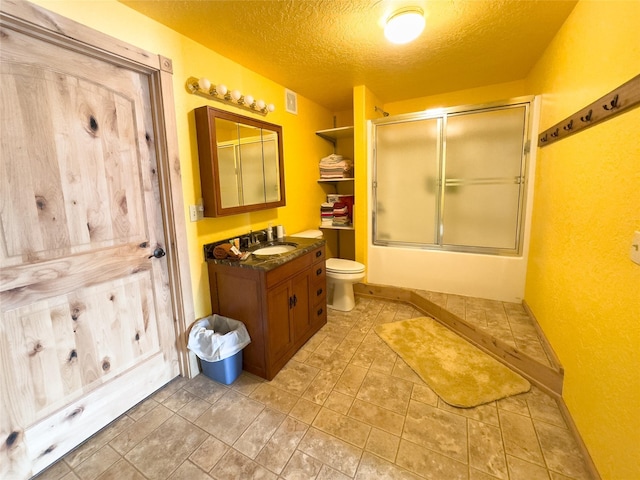 full bath with a textured ceiling, toilet, shower / bath combination with glass door, vanity, and baseboards