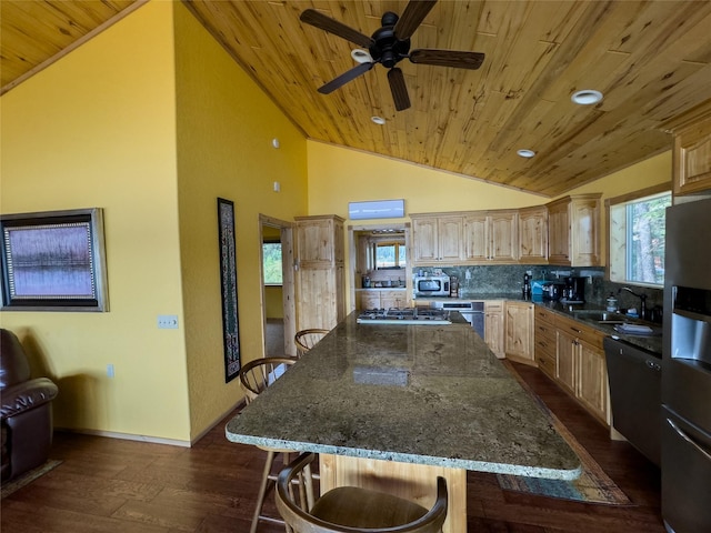 kitchen with vaulted ceiling, appliances with stainless steel finishes, dark stone countertops, and light brown cabinets