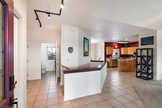 kitchen featuring brown cabinets, stainless steel appliances, light tile patterned flooring, and a peninsula