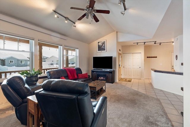 living area featuring track lighting, ceiling fan, tile patterned flooring, and vaulted ceiling