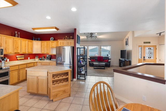 kitchen with light brown cabinets, stainless steel appliances, recessed lighting, light tile patterned floors, and a kitchen island