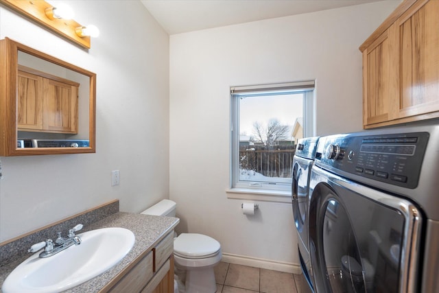 bathroom with toilet, vanity, separate washer and dryer, tile patterned flooring, and baseboards