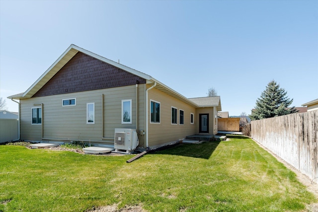 back of house with a fenced backyard, ac unit, and a lawn