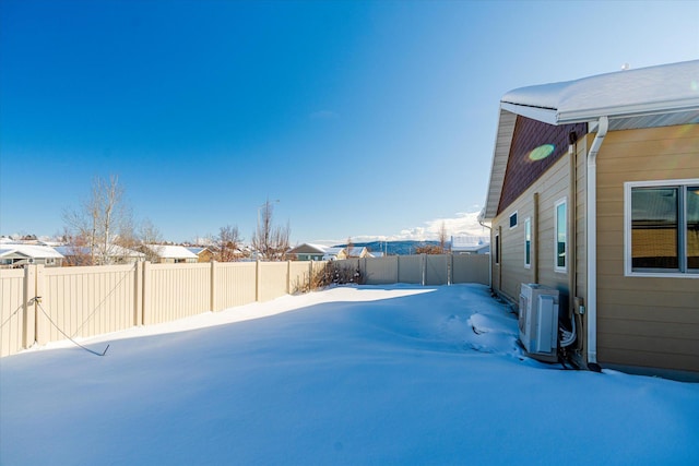 yard covered in snow featuring ac unit and a fenced backyard