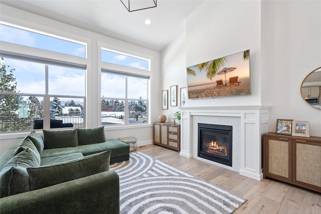 living area featuring baseboards, a glass covered fireplace, recessed lighting, and light wood finished floors