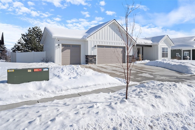 view of front facade featuring an attached garage, fence, board and batten siding, and concrete driveway