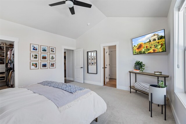 bedroom featuring lofted ceiling, a spacious closet, baseboards, a ceiling fan, and light carpet