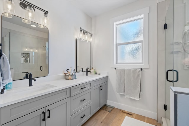 bathroom featuring a stall shower, double vanity, visible vents, and a sink