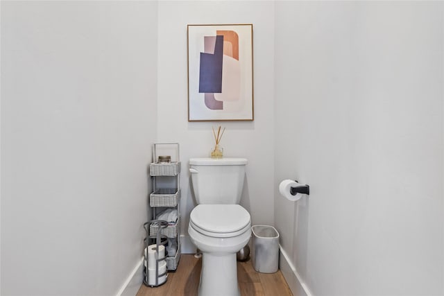 bathroom with toilet, wood finished floors, and baseboards