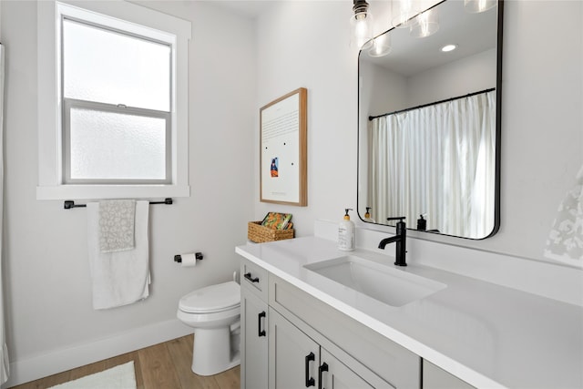 bathroom with a shower with shower curtain, toilet, vanity, wood finished floors, and baseboards