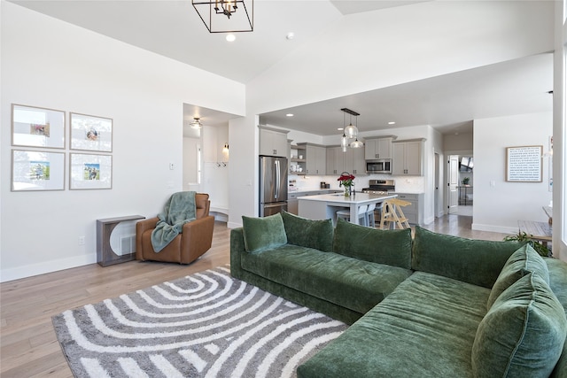 living area featuring high vaulted ceiling, recessed lighting, baseboards, and light wood finished floors