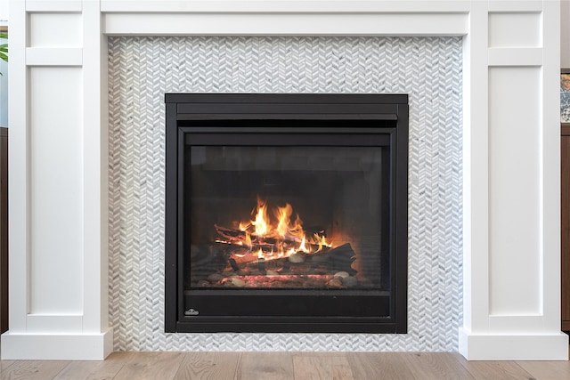 details featuring a tile fireplace and wood finished floors