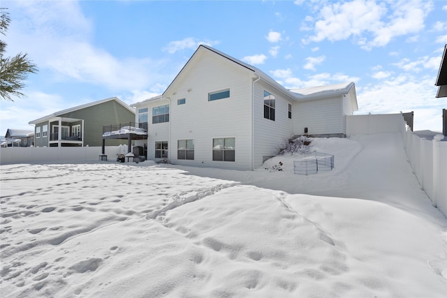 snow covered rear of property with fence