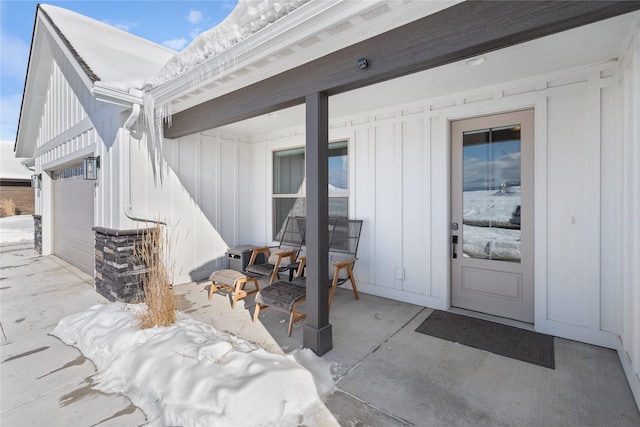 doorway to property featuring stone siding, driveway, a garage, and board and batten siding